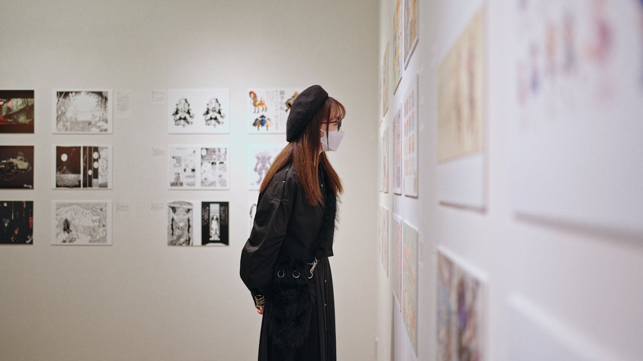 our-story A woman wearing a mask and beret intently views art displays at a gallery in Shinjuku, Tokyo.